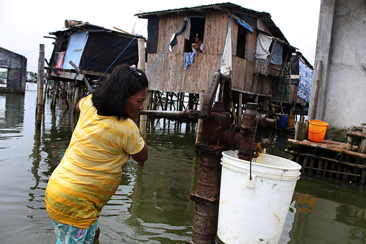 A pregnant woman uses a hand pump to retrieve fresh drinking water during low tide in Sitio Paryahan of Bulacan City, Philippines.