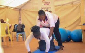 Marygrace Obonyo mostrando a una madre cómo realizar ejercicios de espalda durante el embarazo.