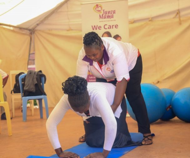 Marygrace Obonyo montrant à une mère comment faire des exercices pour le dos pendant la grossesse.