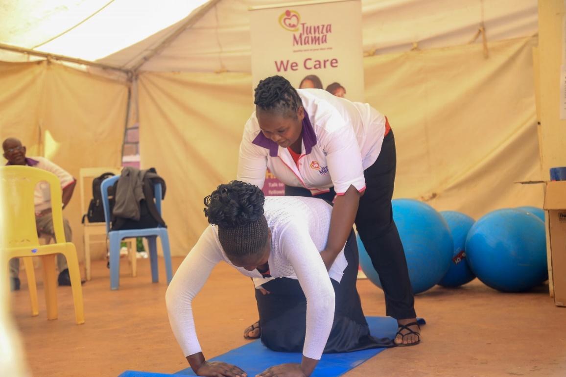 Marygrace Obonyo mostrando a uma mãe como realizar exercícios nas costas durante a gravidez.