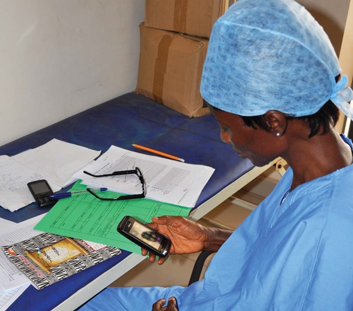 A healthcare provider looks at a cellphone. Image from mHero case study, courtesy of the Digital Health Compendium/The PACE Project
