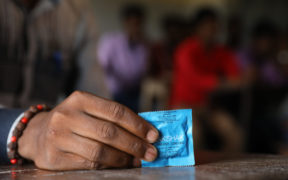 Uma mão segurando um preservativo masculino