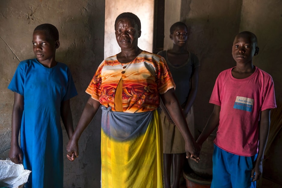 Phoebe Awuco (Orange & Haut blanc), une mobilisatrice communautaire et chef du Self Help Women Group Alita Kole, chez elle avec ses petits-enfants orphelins. Crédit: Jonathan Torgovnik / Getty Images / Images d'autonomisation.