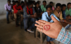 Isang trainer mula sa Pathfinder International na may hawak na male condom