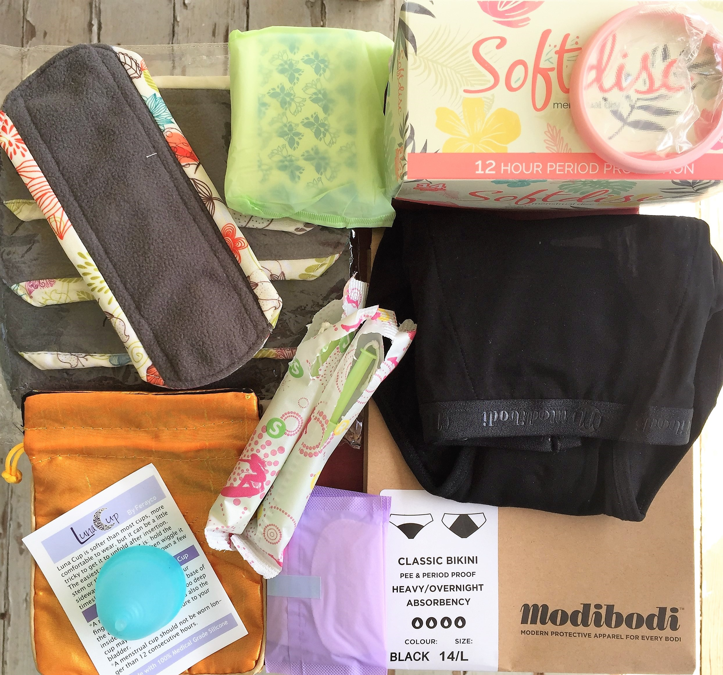 menstrual health supplies: a cloth pad, a pad, a soft cup, panties, a pantyliner, tampons, a menstrual cup