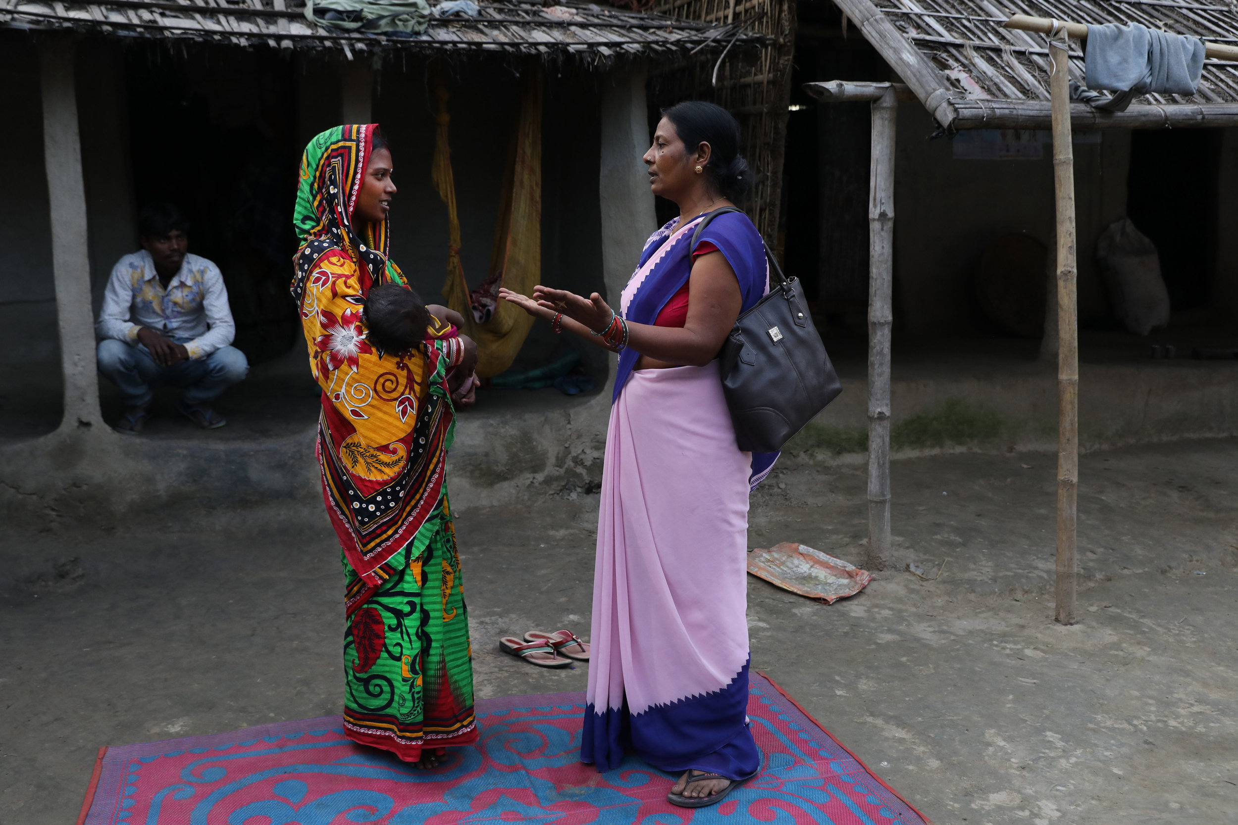 An Accredited Social Health Activist (ASHA) interacts with a young mother during a home visit.