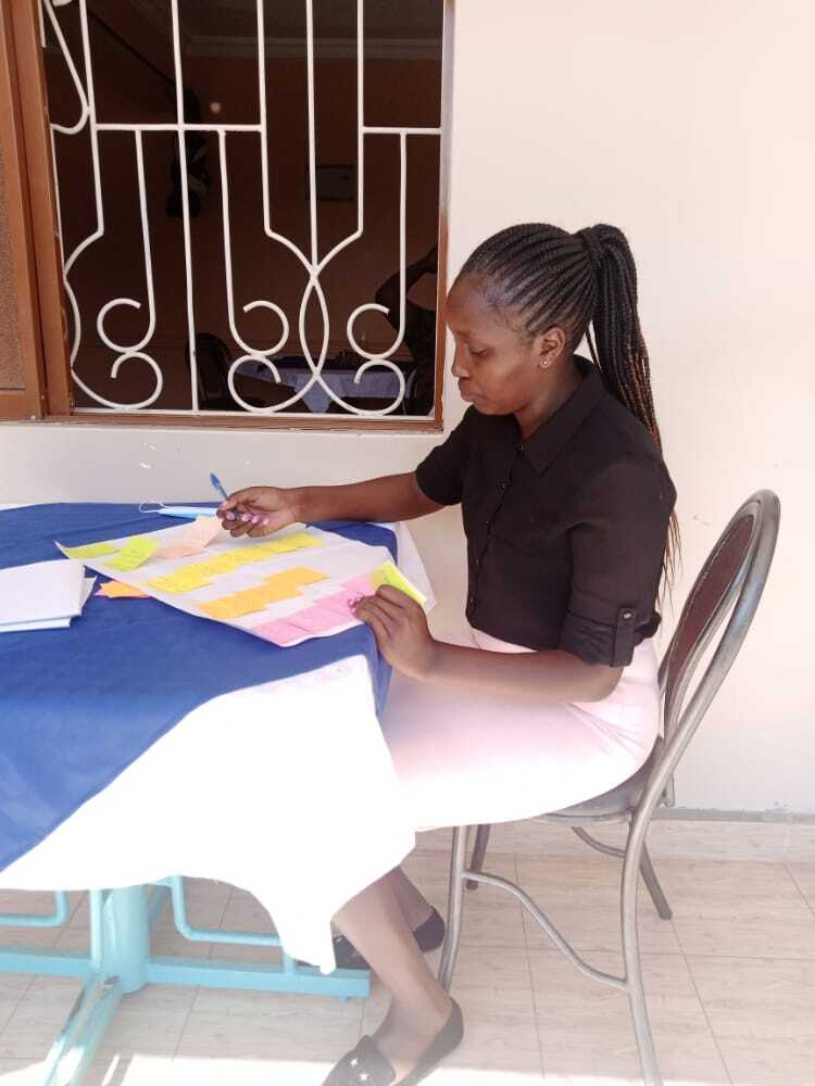 A woman sitting at a table writing on sticky notes.