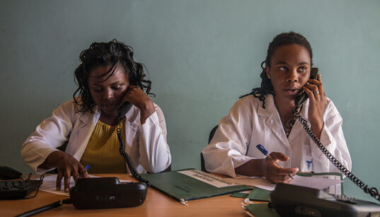 Two female health professionals in Rwanda answering the call lines.