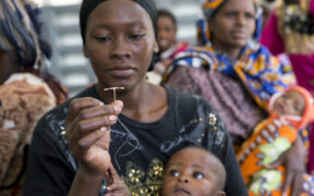 African mother holding baby while examining contraceptive options.