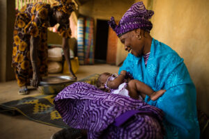 Mother in Sylla Diongto, Senegal holding her infant in a purple cloth.