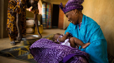 Mother in Sylla Diongto, Senegal holding her infant in a purple cloth.
