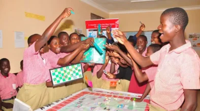 Students from Uganda playing board games standing and cheering