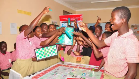 Students from Uganda playing board games standing and cheering