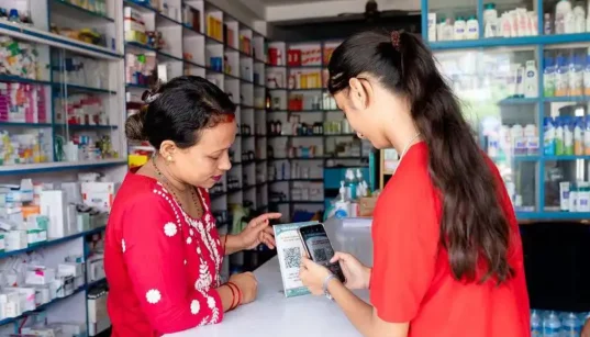 Two women, a pharmacist and a client scanning a QR code with phone camera