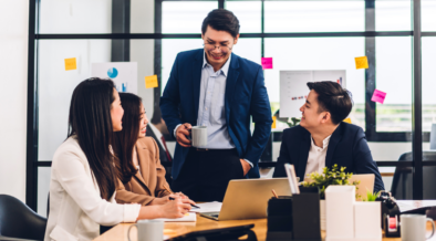 a group of professionals are sitting at an office desk, smiling