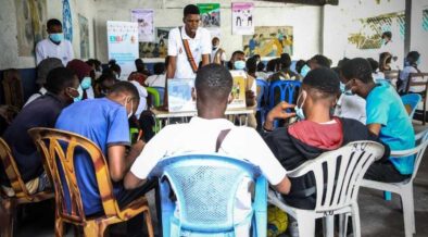 A group of young men in the Democratic Republic of the Congo sit in a circle to speak about reproductive health information and services.