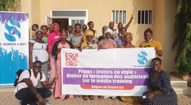 group of people holding a Jeunes en Vigie project banner in front of a building