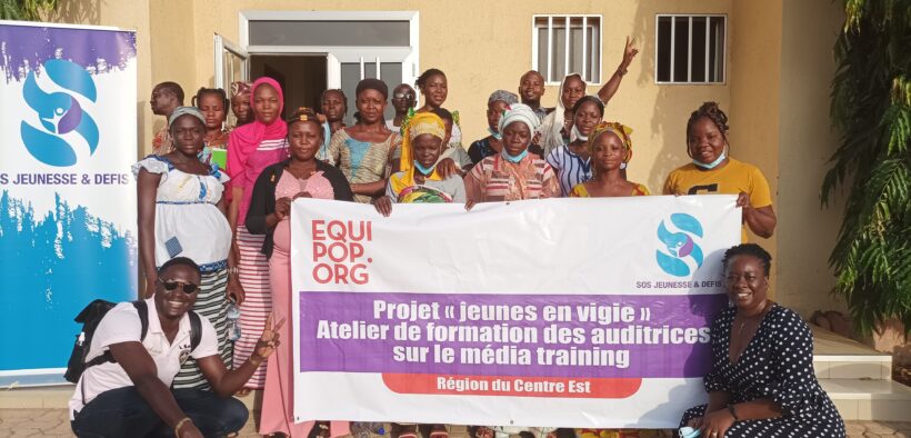 group of people holding a Jeunes en Vigie project banner in front of a building